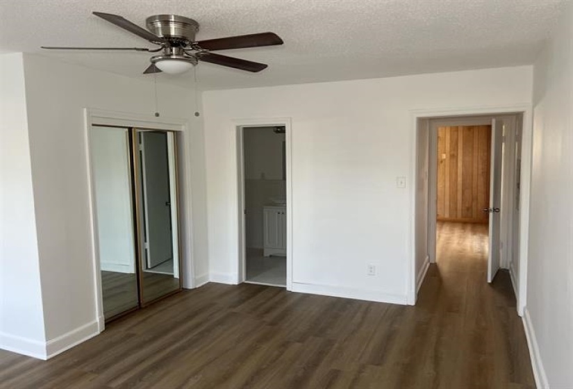 Spacious interior featuring wood-finish flooring, crisp white walls, and a ceiling fan with integrated lighting