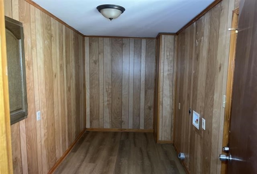 Utility space featuring wood-finish paneling, wood-finish flooring, and a flush-mount ceiling light fixture