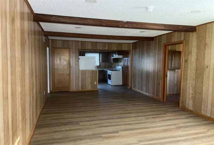 Open-concept living space featuring wood-finish flooring, wood paneling, and exposed ceiling beams