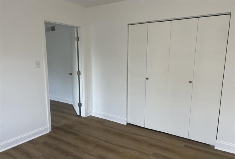 Wardrobe closet with bi-fold doors, wood-finish flooring, white baseboards, and a painted door frame