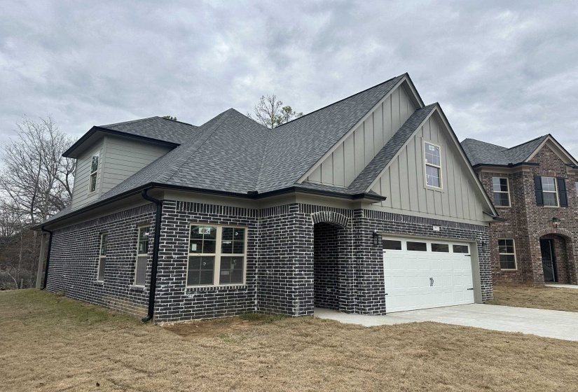View of front of house featuring brick siding, roof with shingles, board and batten siding, concrete driveway, and an attached garage
