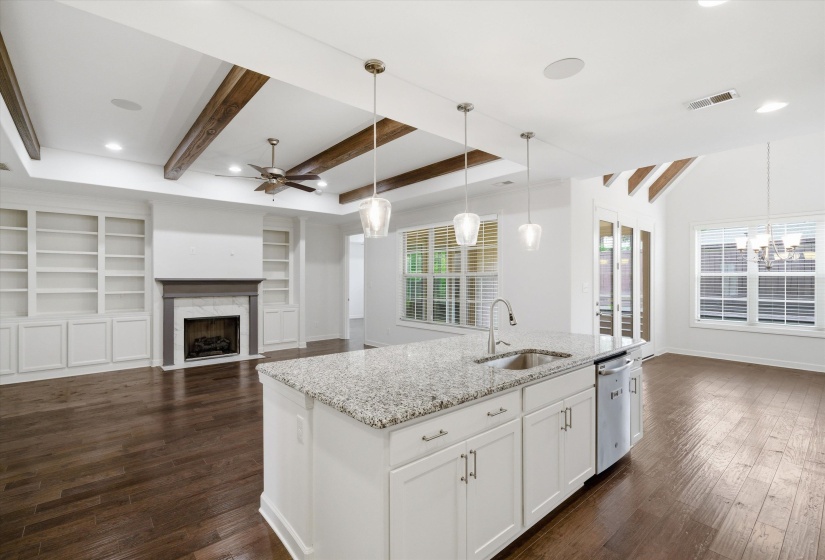 Kitchen island with granite countertop, integrated sink, and pendant lighting