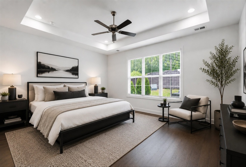Recessed lighting and a ceiling fan illuminate a tray ceiling