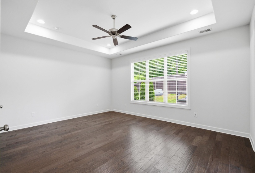 Spacious room featuring rich wood-finish flooring, a coffered ceiling with recessed lighting, and a ceiling fan