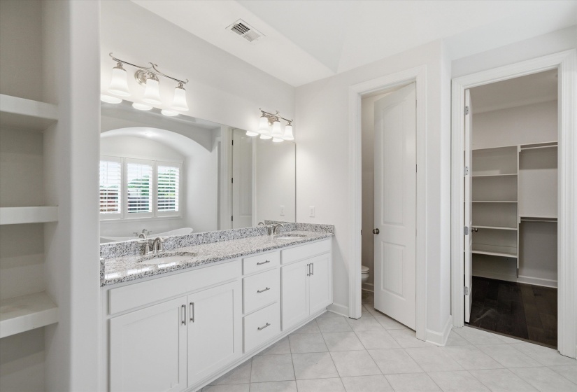 Bathroom featuring a double vanity with stone countertops, integrated sinks, and ample cabinetry