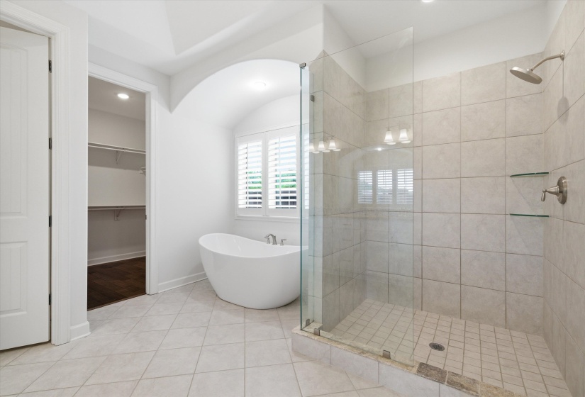 Spacious bathroom featuring a frameless glass shower enclosure with tile surround and integrated glass shelving