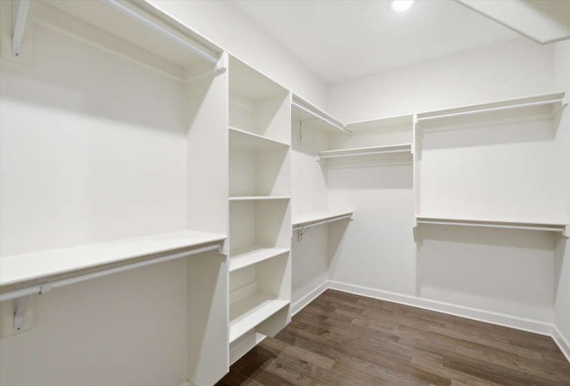 Customizable walk-in closet featuring built-in shelving, multiple hanging rods, corner storage, recessed lighting, and wood-finish flooring