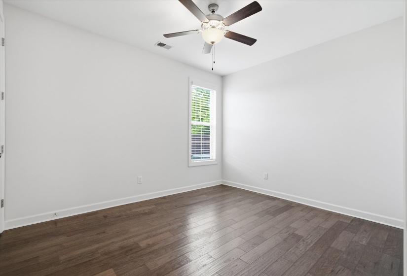 Room featuring wood-finish flooring, a ceiling fan with light fixture, white walls, and a window with blinds
