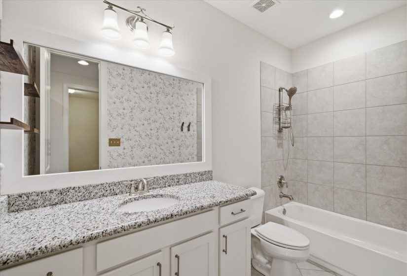 Full bathroom featuring a white vanity with a granite countertop, undermount sink, and brushed nickel faucet