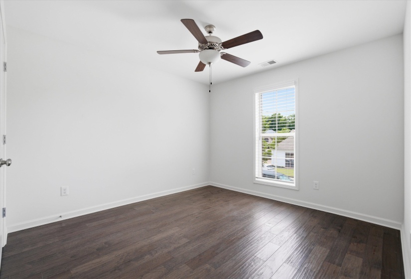 Bright interior space featuring wood-finish flooring and a ceiling fan with integrated lighting