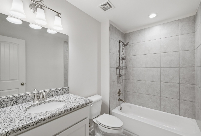 Bathroom featuring a white vanity with a granite-style countertop, undermount sink, and brushed nickel faucet