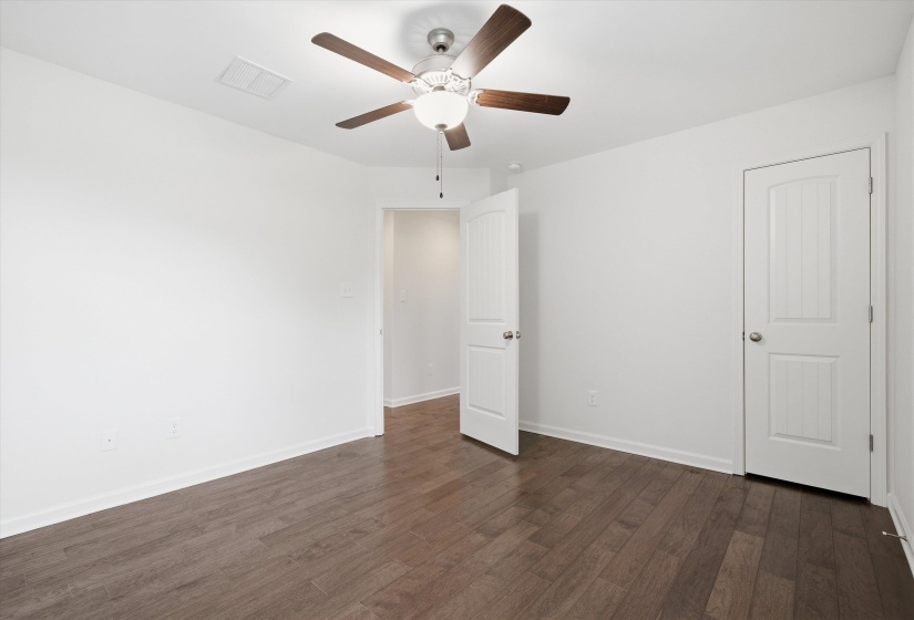 Spacious room featuring wood-finish flooring, a ceiling fan with integrated lighting, white walls, and bright white trim