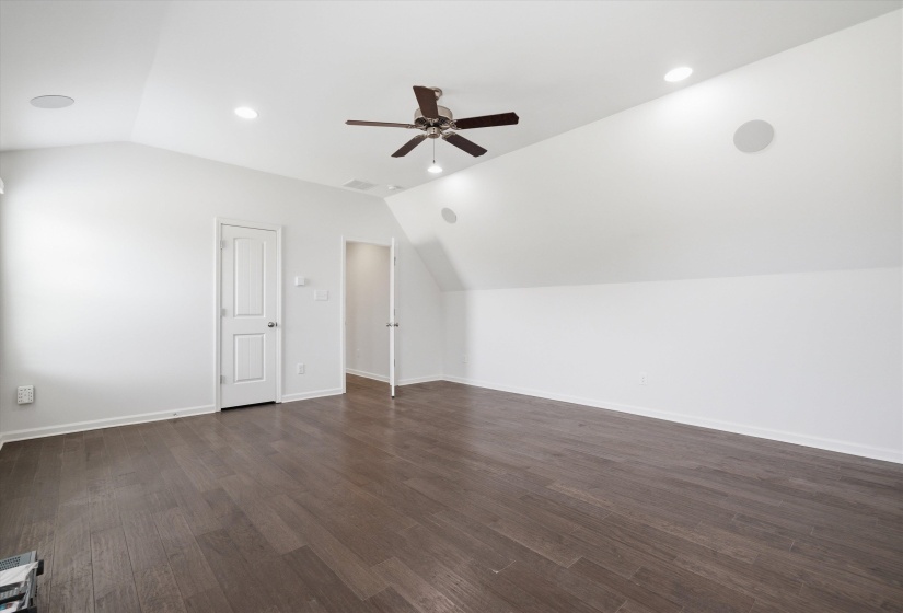 Spacious room featuring wood-finish flooring, vaulted ceilings, and recessed lighting