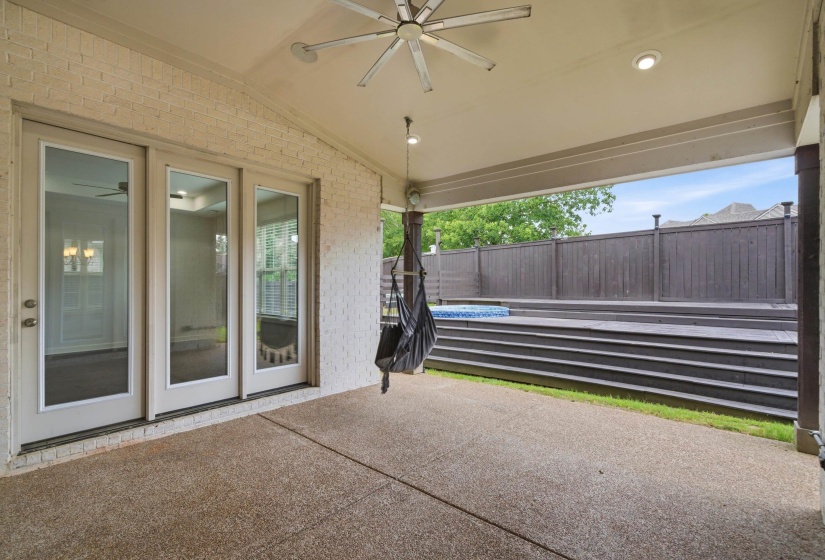 Covered patio featuring an exposed aggregate concrete floor, ceiling fan, and recessed lighting
