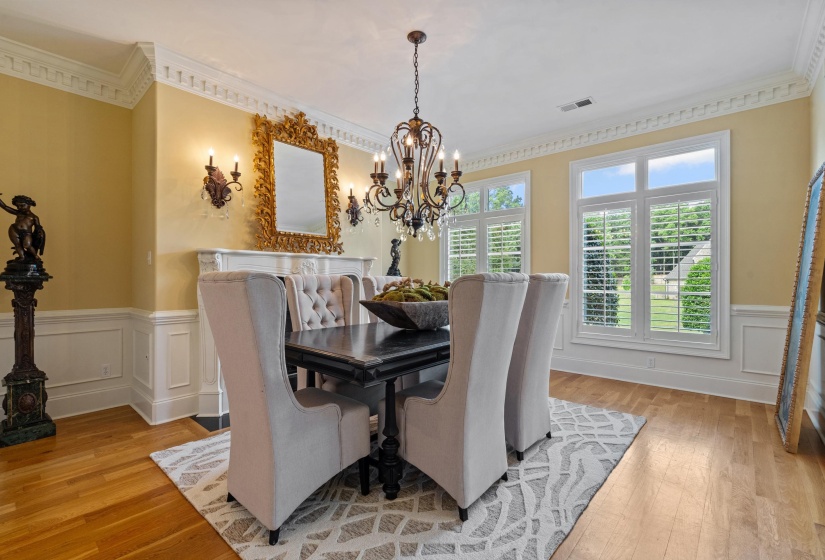 Formal dining space with hardwood-finish flooring, wainscoting, and decorative crown molding