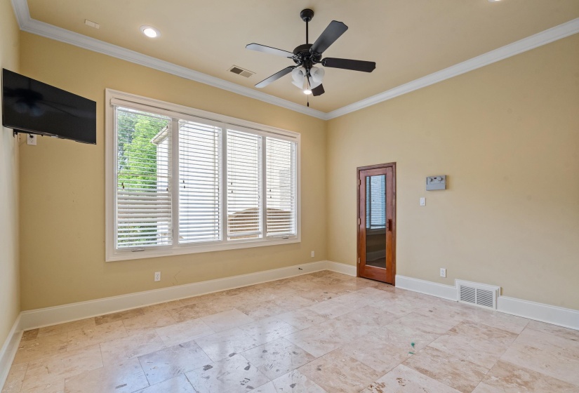 Spacious room featuring large format tile flooring, crown molding, and a ceiling fan with integrated lighting