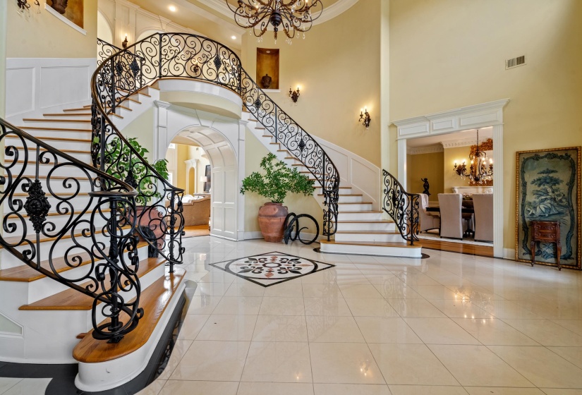 Grand entry foyer featuring a sweeping double staircase with ornate wrought iron balusters and wood treads