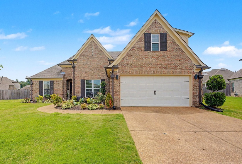 Brick exterior featuring gabled rooflines, an attached two-car garage, and a landscaped front yard