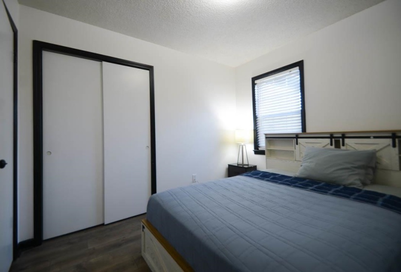 White walls with contrasting black trim surrounding a window and a closet with sliding doors