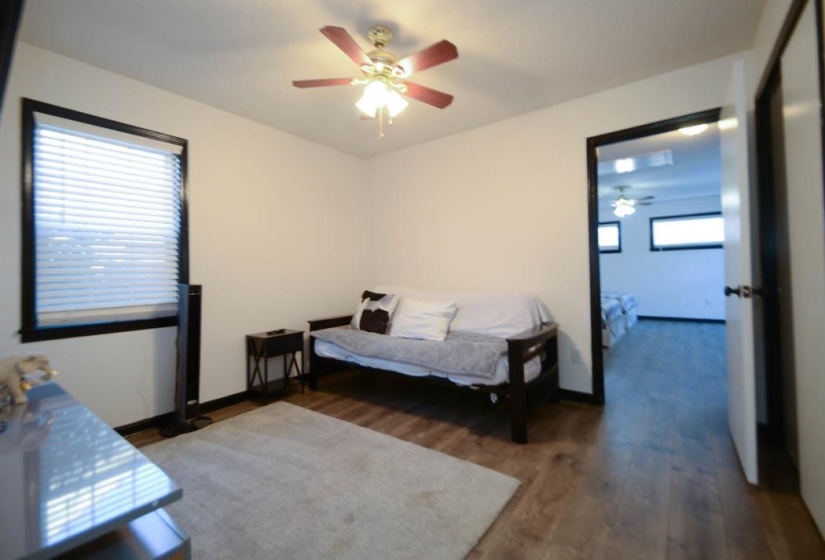 Room featuring wood-finish flooring, a ceiling fan with integrated lighting, and a single window with horizontal blinds