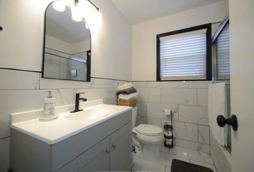 Bathroom featuring a gray vanity with an integrated sink, matte black faucet, and an arched framed mirror