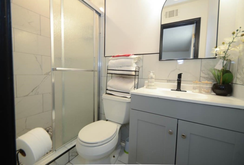 Contemporary bathroom with a gray vanity, matte black faucet, and a wall-mounted arched mirror