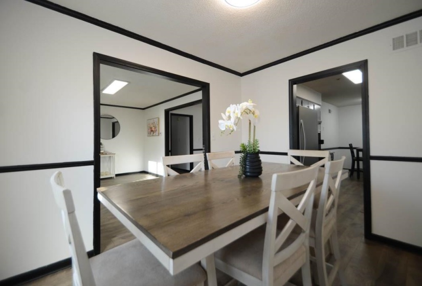 Dining area featuring wood-finish flooring, white walls with dark trim, and a flush-mount ceiling light