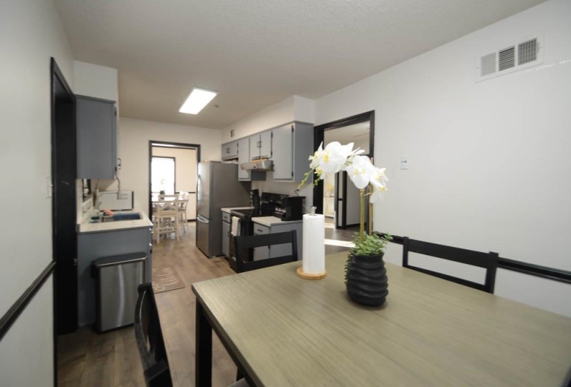 Modern kitchen featuring wood-finish flooring, grey cabinetry, stainless steel appliances, and a recessed ceiling light