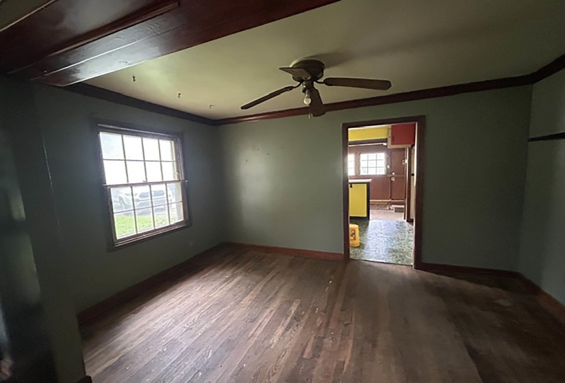 Spacious room featuring wood-finish flooring, a ceiling fan, and a window with a grid pattern