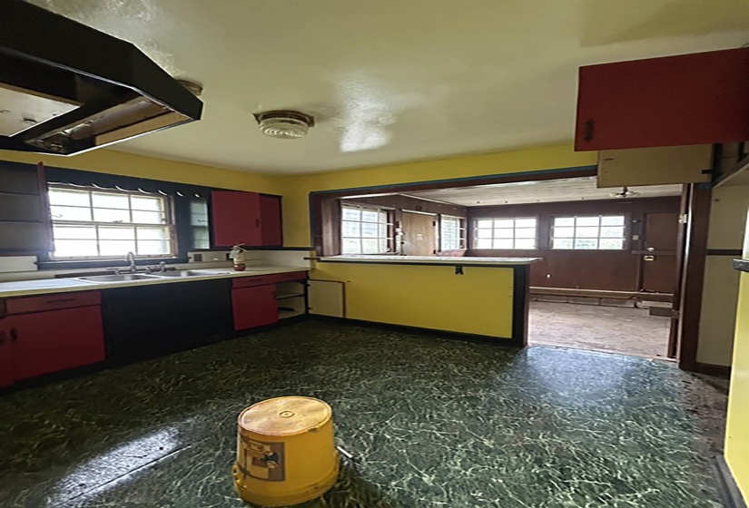 Kitchen featuring a double basin stainless steel sink, red and black cabinetry, yellow walls, and green patterned flooring