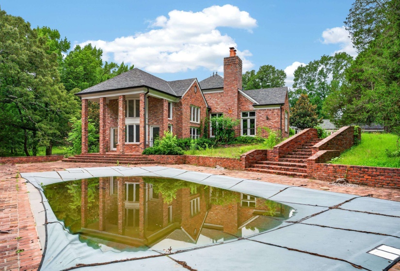 Brick exterior with a covered pool, multiple outdoor brick staircases, and a stately portico with tall columns