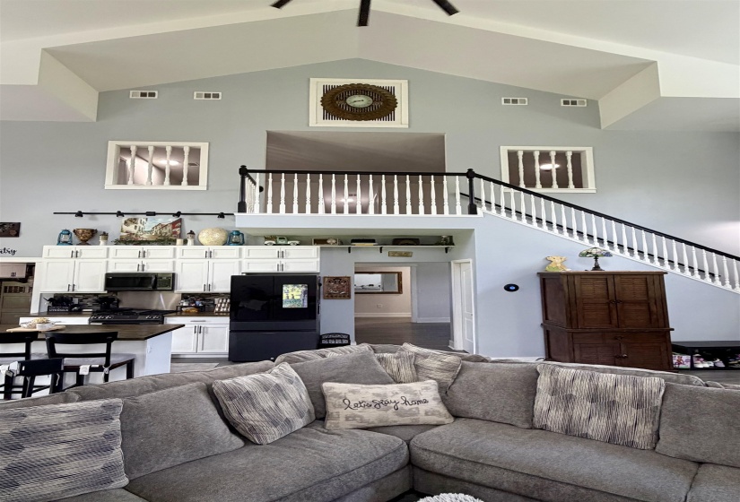 Vaulted ceilings featuring a ceiling fan and upper windows
