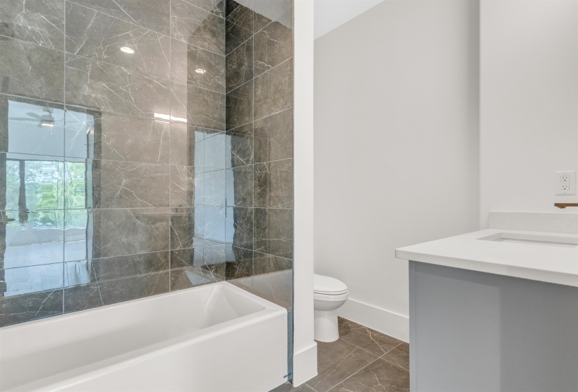 Full bath featuring vanity and marble look tile flooring