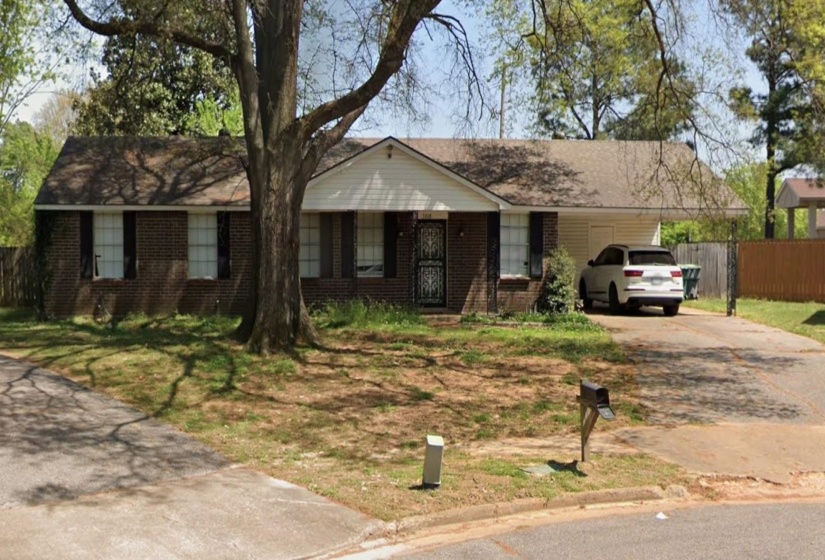 Brick exterior with white trim, featuring a paved driveway and an attached garage