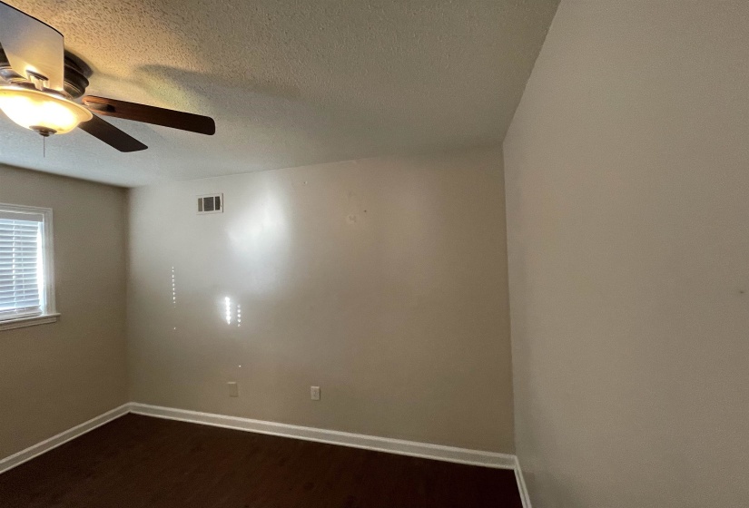 Room featuring wood-finish flooring, a ceiling fan with integrated lighting, and a window with blinds