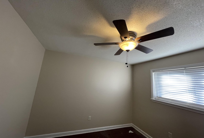 Ceiling fan with integrated lighting, textured ceiling, light-toned walls, a single window with blinds, and dark wood-finish flooring