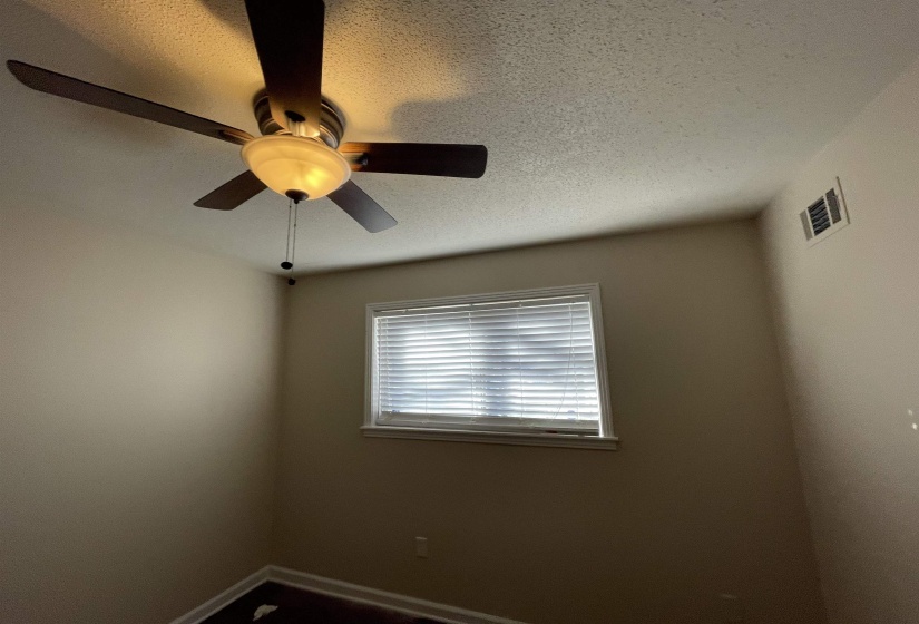 Room featuring a ceiling fan with integrated lighting, a window with horizontal blinds, and a wall-mounted vent