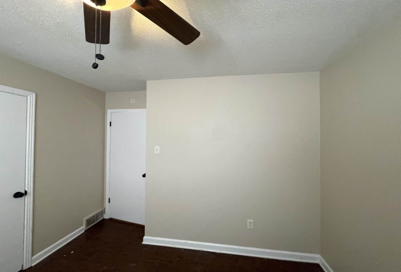 Interior room featuring wood-finish flooring, light neutral-toned walls, and white baseboards