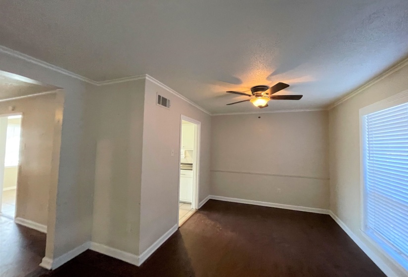Interior space featuring dark wood-finish flooring, light-toned walls, and white crown molding