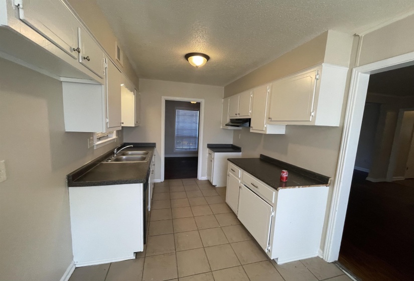 Galley kitchen with light-toned tile flooring