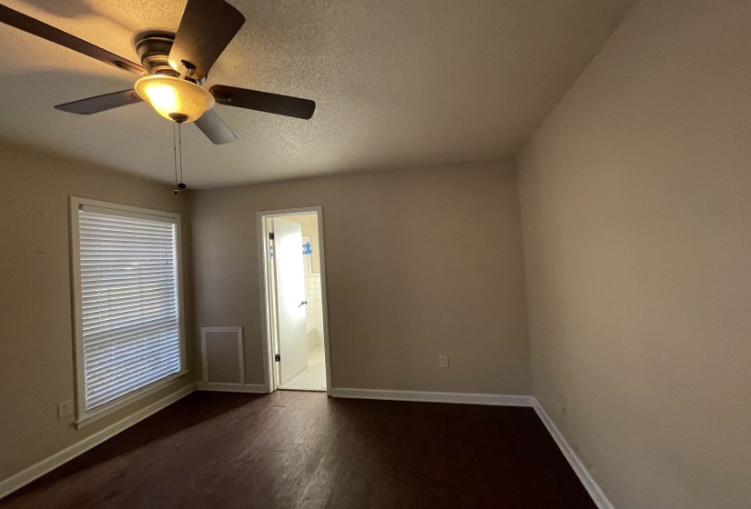 Interior room featuring wood-finish flooring, a ceiling fan with integrated lighting, window with horizontal blinds, and a doorway opening to an additional room