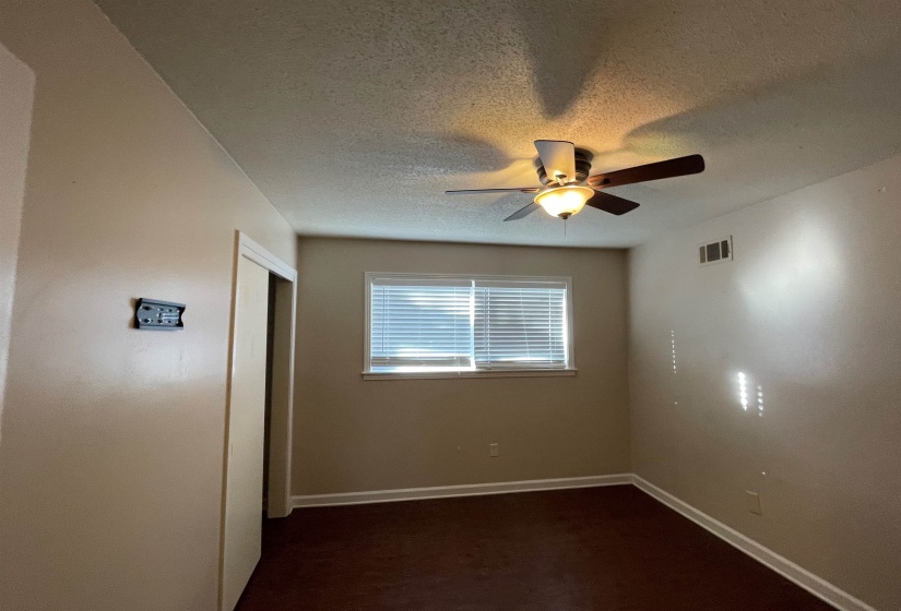 Interior room featuring a ceiling fan with integrated lighting, a double-pane window with blinds, and wood-finish flooring