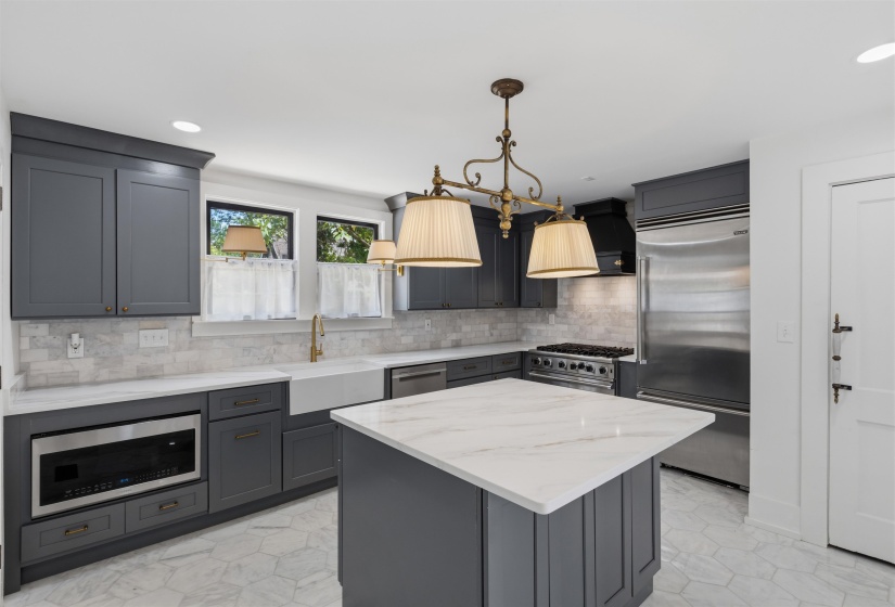 Modern kitchen featuring gray cabinetry, a central island with a white countertop, and stainless steel appliances