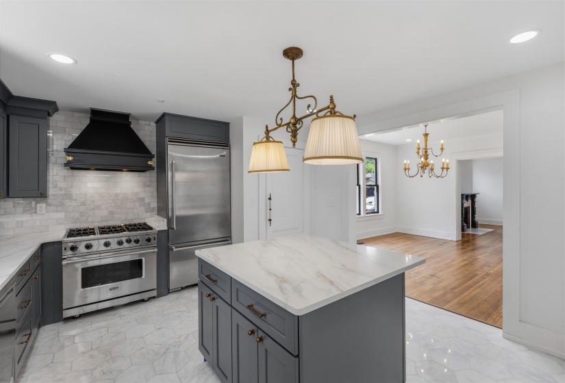 Kitchen featuring dark gray cabinetry, stainless steel appliances, a white tile backsplash, and a central island with a white countertop