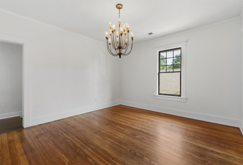 Interior room featuring wood-finish flooring, white walls, and a multi-arm chandelier