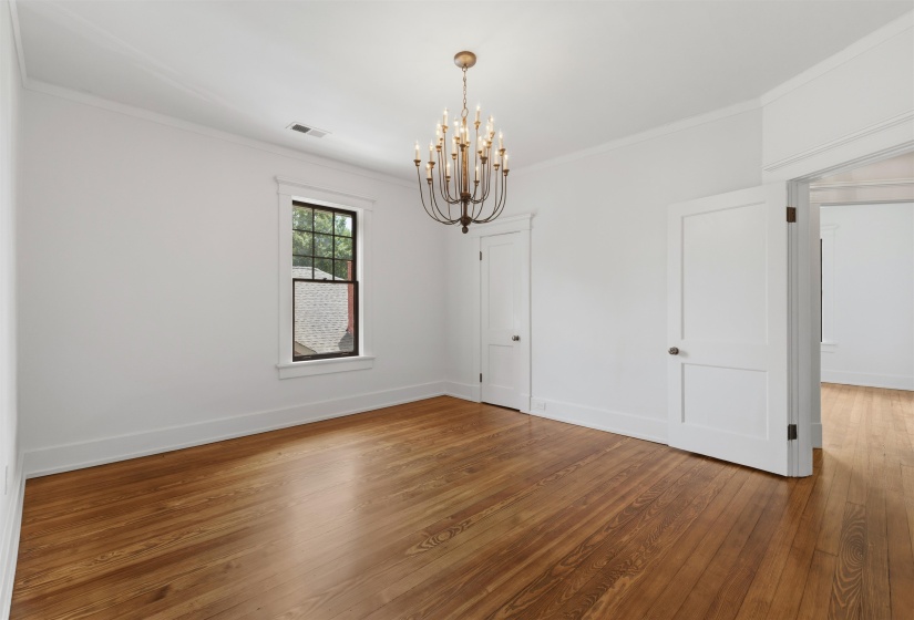 Hardwood flooring extending throughout, complemented by a multi-arm chandelier