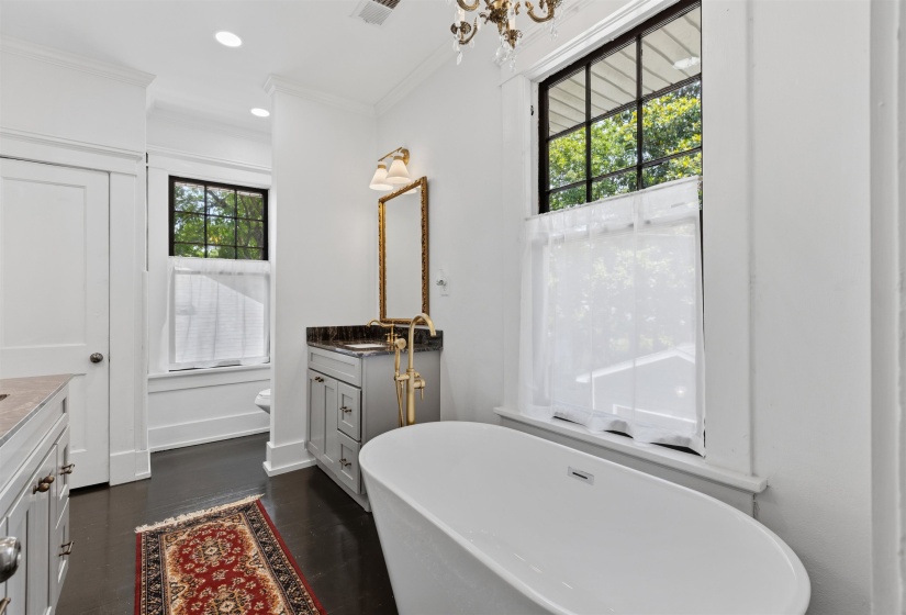 Freestanding soaking tub with dark wood-finish flooring