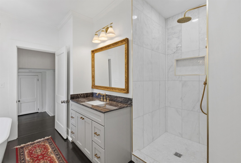Walk-in shower featuring large format white tile, a built-in niche with mosaic tile, and gold-finish fixtures