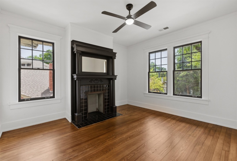Hardwood flooring and a black tiled fireplace with mantel