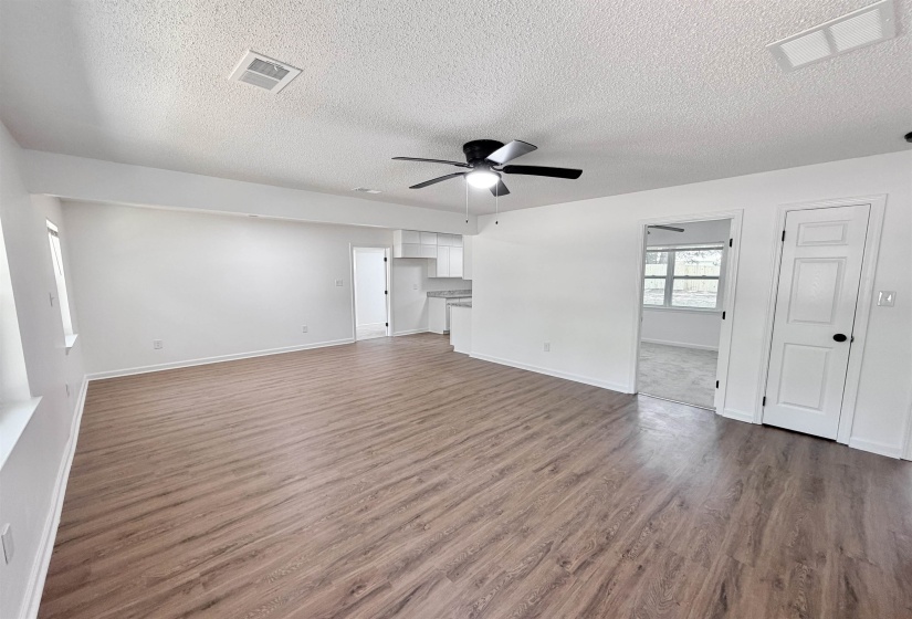 Spacious interior featuring wood-finish flooring, white walls, and a ceiling fan